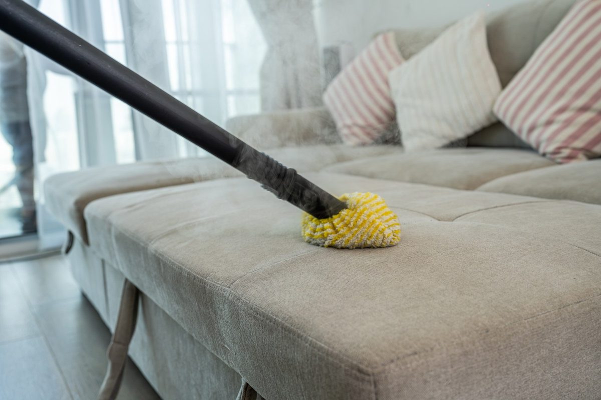 Cleaner vacuuming a sofa